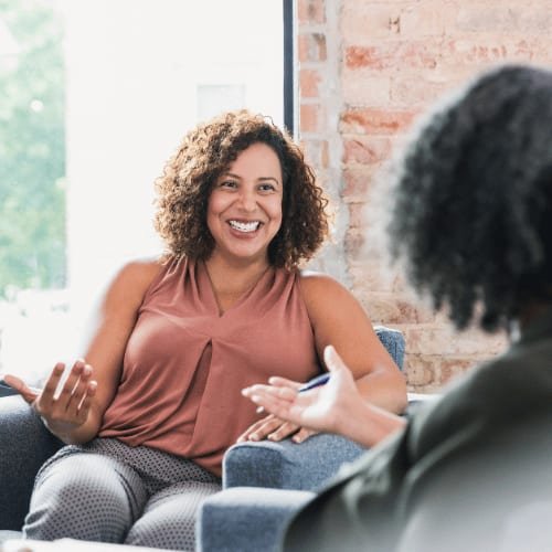 Two people talking on a sofa in a bright room